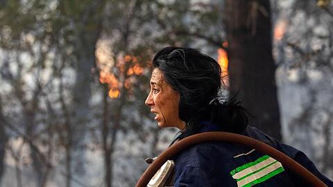 Eine Feuerwehrfrau versucht ein Feuer etwa 30 Kilometer von der griechischen Hauptstadt Athen zu l&ouml;schen. Vielerorts sind die Br&auml;nde au&szlig;er Kontrolle geraten, es kommt zunehmend internationale Hilfe an.