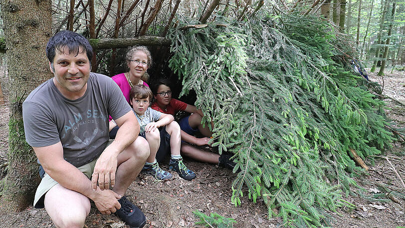 Die Brams im selbstgebauten Zelt aus Fichtenzweigen und Reisig. Sie sind gespannt auf die erste Nacht im Wald.