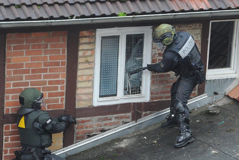 Die Besetzer werfen Konfetti, unten steht ein SEK-Kommando der Polizei: In Greifswald wurde ein besetztes Haus geräumt. Die Bilder.