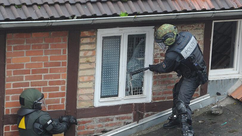 Die Besetzer werfen Konfetti, unten steht ein SEK-Kommando der Polizei: In Greifswald wurde ein besetztes Haus geräumt. Die Bilder.