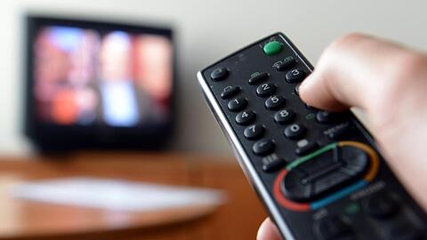 Eine Hand hält eine Fernbedienung für ein Fernsehgerät.