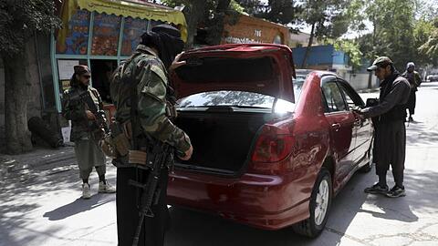 Taliban-Kämpfer durchsuchen ein Fahrzeug an einem Kontrollpunkt in Kabul.