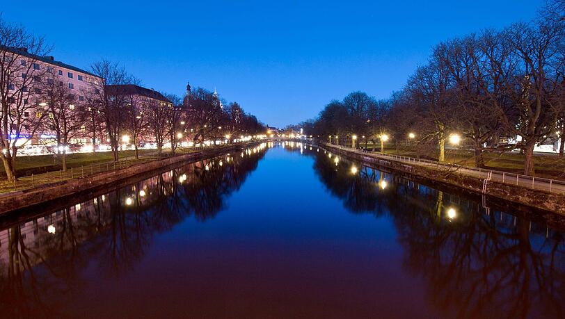Idyllisches München: Der Abendhimmel und diverse Straßenlichter spiegeln sich auf der ruhigen Wasseroberfläche der Isar, Idyllisches München: Der Abendhimmel und diverse Straßenlichter spiegeln sich auf der ruhigen Wasseroberfläche der Isar,