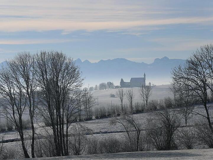 Von Frost umgeben steht die Wallfahrtskirche Sankt Alban vor dem Panorama der Alpen im Sonnenschein. Foto: Karl-Josef Hildenbrand