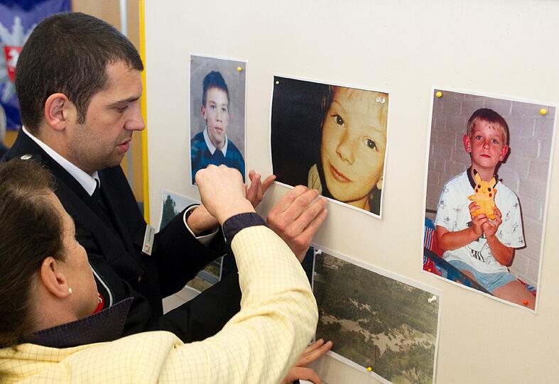 Polizeibeamte Susanne Schimmelpfennig (l.) und Josef Schade kleben die Fotos der ermordeten Jungen Stefan J., Dennis R. und Dennis K. sowie deren Fundorte am Freitag bei der Pressekonferenz der SOKO Dennis an die Wand.