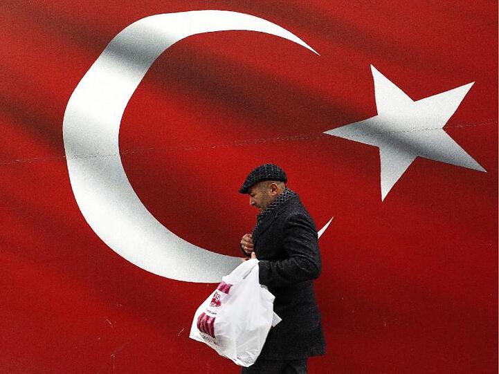 Ein Mann geht an einer türkischen Flagge vorbei.