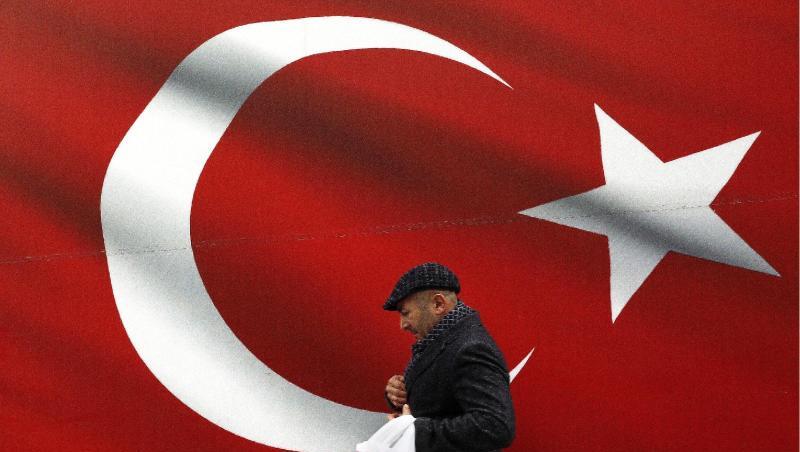 Ein Mann geht an einer türkischen Flagge vorbei.