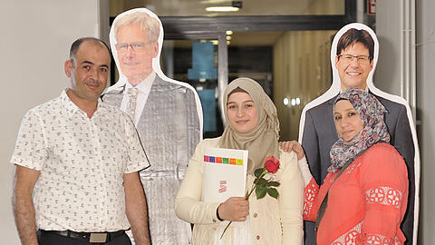 Abdulmunaam Abdulhadi (l.), seine Tochter Rama und ihre Mutter Tahani. Wegen Corona sind bei der Abiturzeugnisvergabe die Schulleiter Reinhard Rolvering und der Oberstufenkoordinator des Gymnasiums Neubiberg, Philipp Holly, nur als Pappfiguren anwesend.