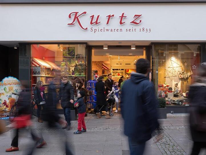 Menschen laufen am Stuttgarter Traditionsunternehmen Spielwaren Kurtz in Stuttgart vorbei.