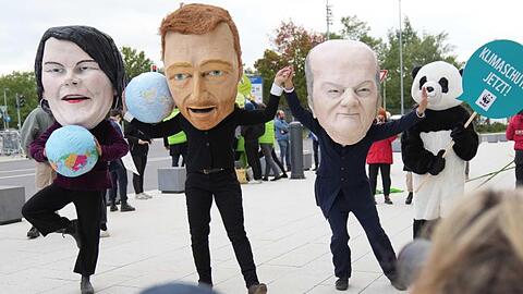 Klimaschutzaktivisten protestieren mit Masken, die Annalena Baerbock, Christian Lindner und Olaf Scholz darstellen sollen.