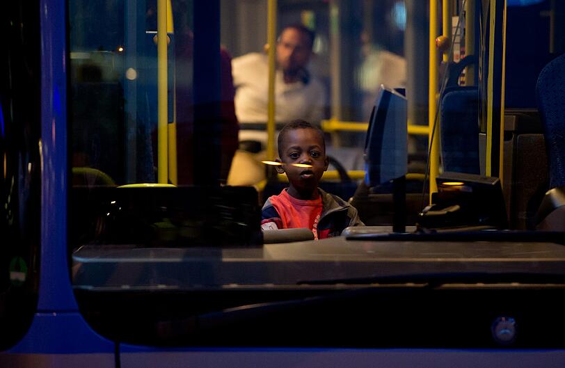 Warten auf die Weiterfahrt: Ein kleiner Bub sitzt nach seiner Ankunft in München in einem Bus.