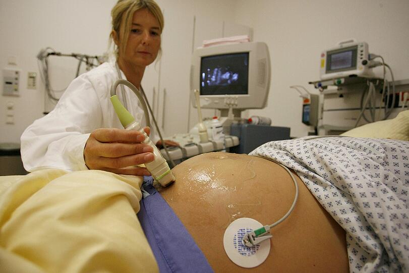 Eine Hebamme führt am 14.10.2009 in der Frauenklinik in Erlangen (Bayern) an einer schwangeren Patientin eine Ultraschall-Untersuchung durch. Eine Hebamme, die Geburtshilfe anbietet, muss ab Juli 2014 jährlich 5091 Euro für ihre Versicherung aufbringen, da die Prämien für die Haftpflichtsversichung wieder stark angehoben werden.