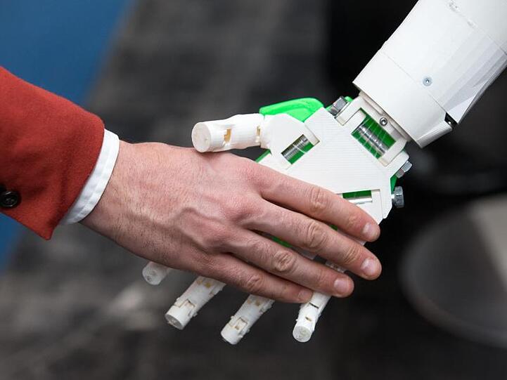 Ein humanoider Roboter gibt einem Menschen die Hand am Stand von ioX Lab bei der IT-Messe CeBIT. Foto: Friso Gentsch/Archiv