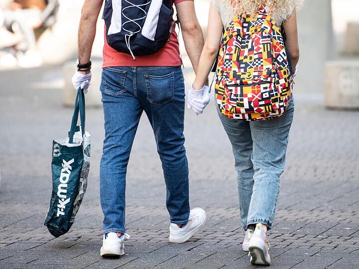 Ein Pärchen trägt während eines Einkaufsbummels auf der Schildergasse in Köln Schutzhandschuhe.