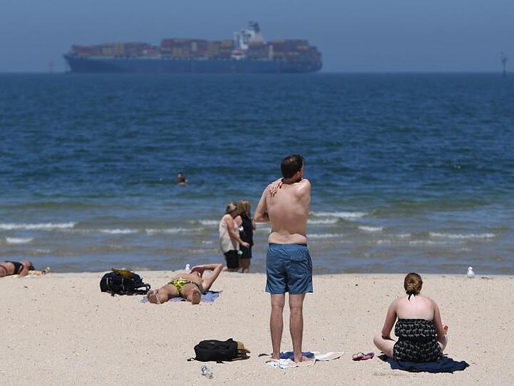 Strandbesucher sonnen sich am Port Melbourne Beach.
