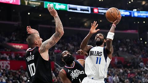 Kyrie Irving (r) von den Dallas Mavericks wirft unter dem Druck von James Harden (M) und Daniel Theis von den Los Angeles Clippers.