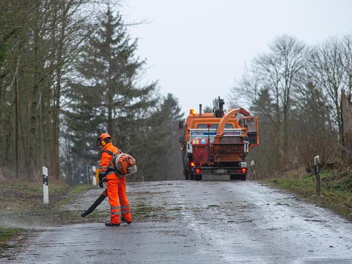 Ein Arbeiter beseitigt mit einem Gebläse Rinde und Äste von einer Straße. Foto: Klaus-Dietmar Gabbert/dpa-Zentralbild/dpa