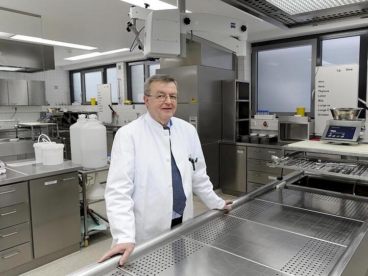 Der Gerichtsmediziner Wolfgang Eisenmenger steht hinter einem stählernen Seziertisch. Foto: Peter Kneffel/Archiv