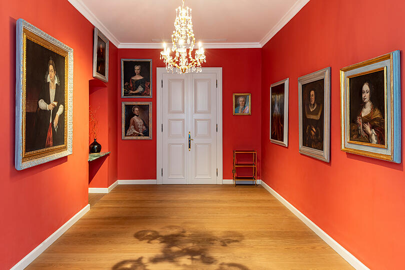 Der Portrait Salon besticht durch kräftiges Rot und alte Gemälde.