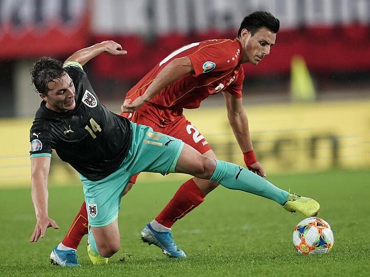 Österreichs Julian Baumgartlinger (l) kämpft mit Eljif Elams aus Nordmazedonien um den Ball.