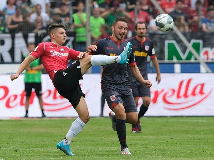 Hannovers Florent Muslija (l.) und Regensburgs Marco Grüttner kämpfen um den Ball. Foto: Peter Steffen