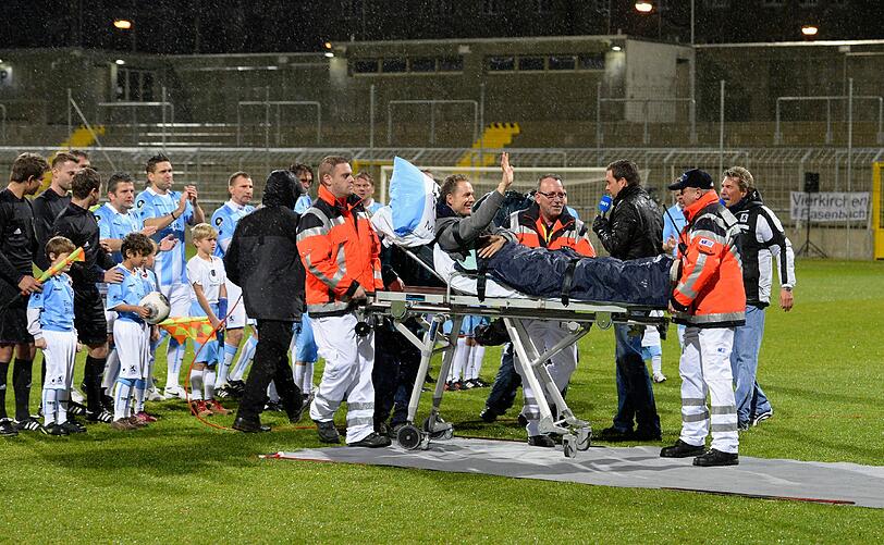Olaf Bodden wird auf einem Krankenbett auf den Rasen des Grünwalder Stadions gefahren.
