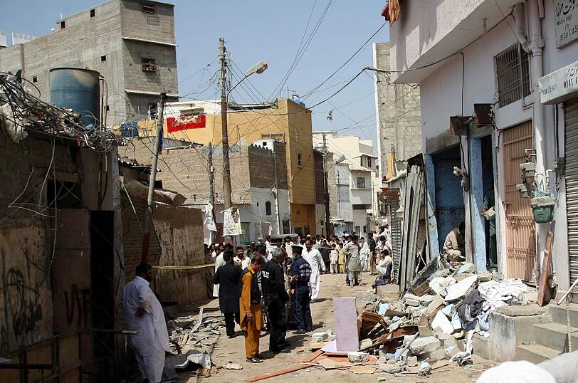 Pakistanische Sicherheitskräfte inspizieren den Ort einer Bombenexplosion, die einen Polizist und zwei weitere Zivilisten in Karachi mit in den Tod gerissen hat.