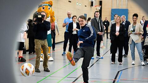 Karl Lauterbach (SPD), Bundesminister für Gesundheit, schießt einen Fußball auf eine Torwand.