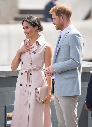 Herzogin Meghan besucht mit ihrem Gatten Prinz Harry eine Ausstellung zu Ehren von Nelson Mandela. Das baby-rosa-farbene Trenchkleid passt perfekt zum baby-blauen Linon Sakko.