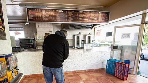 Der Inhaber eines Döner-Imbiss fegt in seinem Geschäft in Walkraiburg Scherben zusammen. Foto: Matthias Balk/dpa/Archivbild
