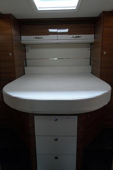 Das Hochbett im Heck ruht auf einem Regal mit Schubladen, links und rechts gibt es Wandschränke.