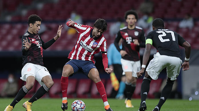 Joao Felix (M.) von Atletico Madrid kämpft mit Jamal Musiala (l) vom FC Bayern um den Ball.
