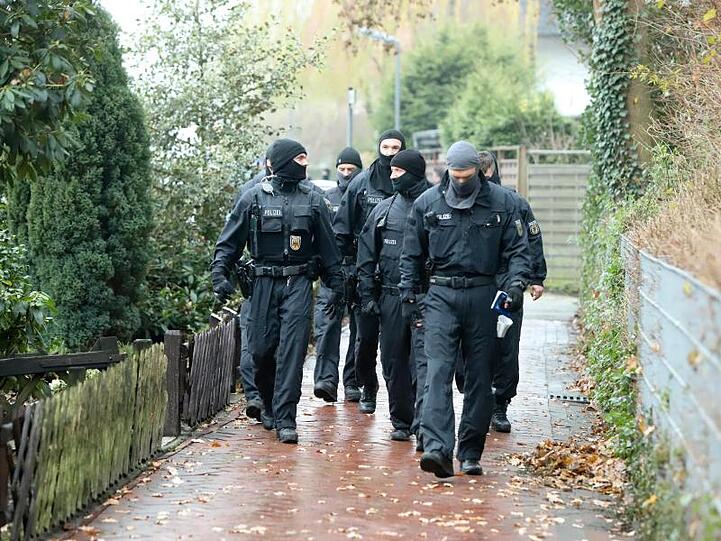 Mehrere vermummte Polizisten gehen an einem Haus entlang. Foto: Christian Butt/TNN/Archiv