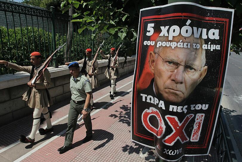 &bdquo;Seit fünf Jahren saugt er euer Blut &ndash; sagt Nein zu ihm&ldquo;, steht auf dem Wahlplakat in Athen. Links paradiert die Präsidentengarde.