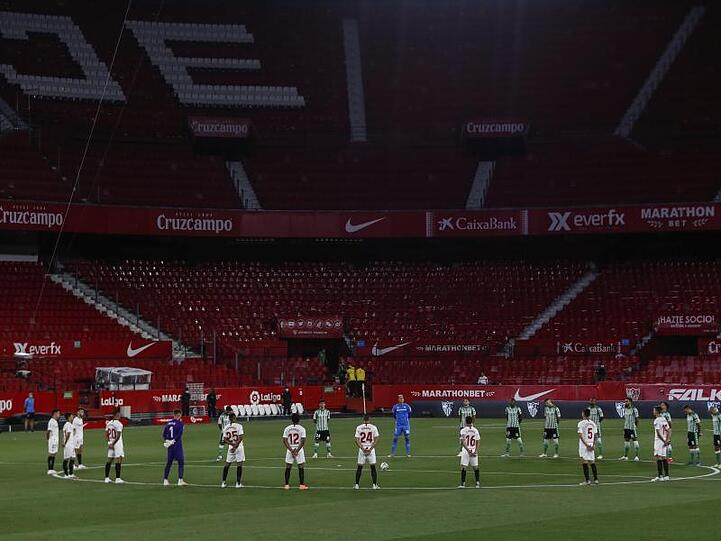 Spieler des FC Sevilla und Real Betis Sevilla legen eine Schweigeminute für die Coronavirus-Todesopfer ein.