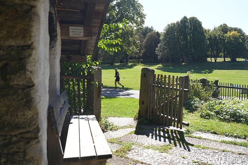 Der Ausblick vom Bayerwaldhaus in den Westpark. Hinter dem Holzzaun sieht man einen Jogger laufen.