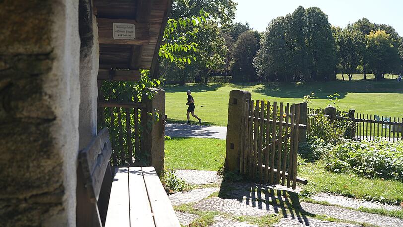 Der Ausblick vom Bayerwaldhaus in den Westpark. Hinter dem Holzzaun sieht man einen Jogger laufen. Der Ausblick vom Bayerwaldhaus in den Westpark. Hinter dem Holzzaun sieht man einen Jogger laufen.