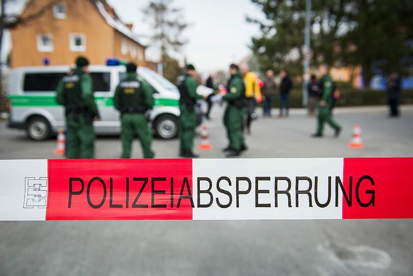 Polizeibeamte stehen in der Evakuierungszone hinter einer Absperrung.