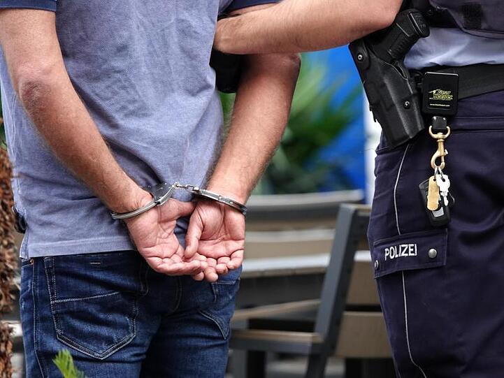 Ein Mann wird in Handschellen abgeführt. Foto: Johannes Neudecker/dpa/Symbolbild