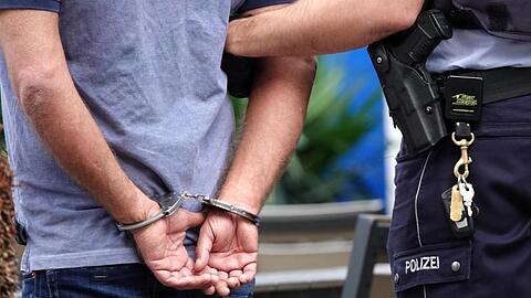 Ein Mann wird in Handschellen abgeführt. Foto: Johannes Neudecker/dpa/Symbolbild