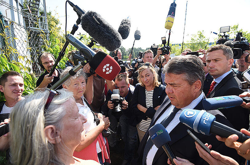 Bundeswirtschaftsminister Sigmar Gabriel (M) wird in Heidenau von Journalisten umringt.