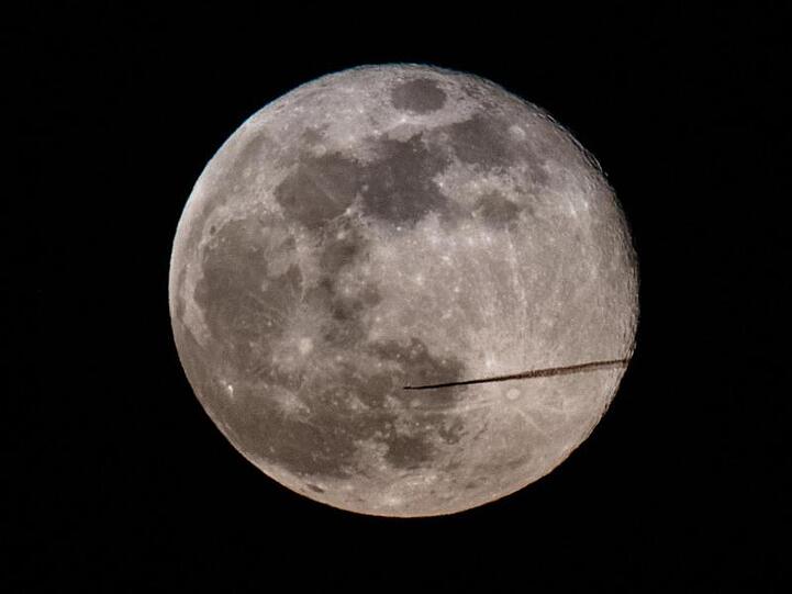 Ein Blick auf die Erde. Ein Flugzeug fliegt am Abend am Vollmond vorbei. Foto: Robert Michael/Archiv