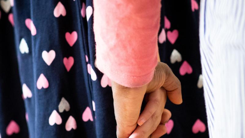 Eine Frau hält ein Mädchen an der Hand.