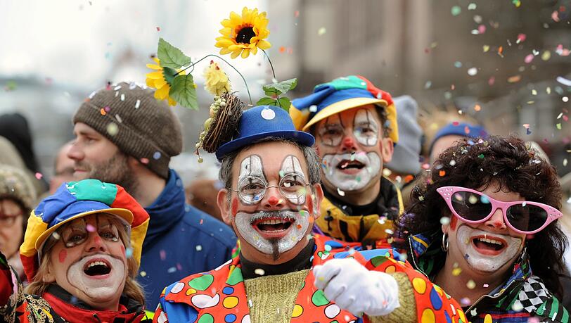 Besucher in Clown-Kostümen werfen in Nürnberg beim Faschingsumzug mit Konfetti.