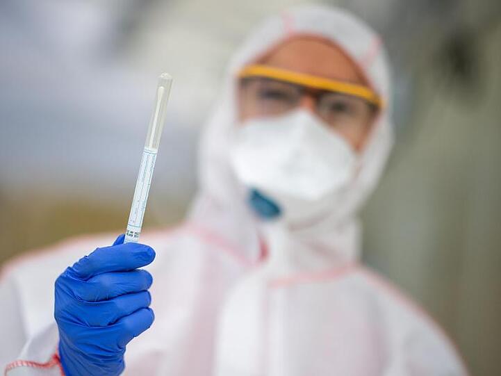 Ein Mitarbeiter hält in einem Abstrichzentrum einen Coronatest-Abstrich in der Hand. Foto: Sebastian Gollnow/dpa/Symbolbild