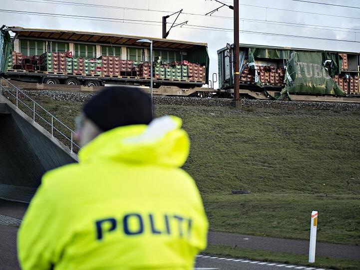 Ein Polizist steht vor einem beschädigten Güterzug, nahe der Brücke über den Großen Belt bei Nyborg. Die dänische Polizei berichtet, dass mehrere Menschen hier bei einem Zugunglück getötet wurden.