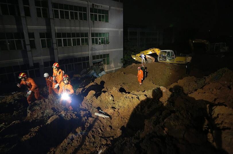 Rettungskräfte durchsuchen die Erdmassen rund um ein eingestürztes Fabrikgebäude nach einem Erdrutsch in Südchina. Mindestens 90 Personen werden vermisst.