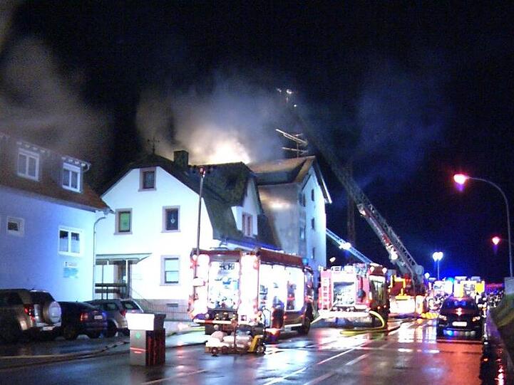 Feuerwehrleute löschen den Brand in einem Mehrfamilienhaus im rheinland-pfälzischen Lambrecht.