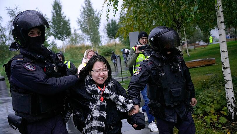 Polizisten in Moskau halten eine Demonstrantin fest.