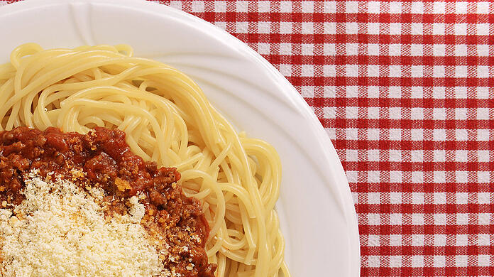 Ein Teller voller dampfender Spaghetti mit Bolognesesoße und Parmesan.